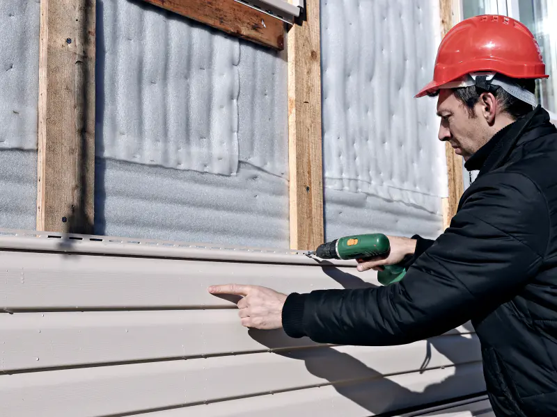 contractor using a drill during siding installation service meridian id